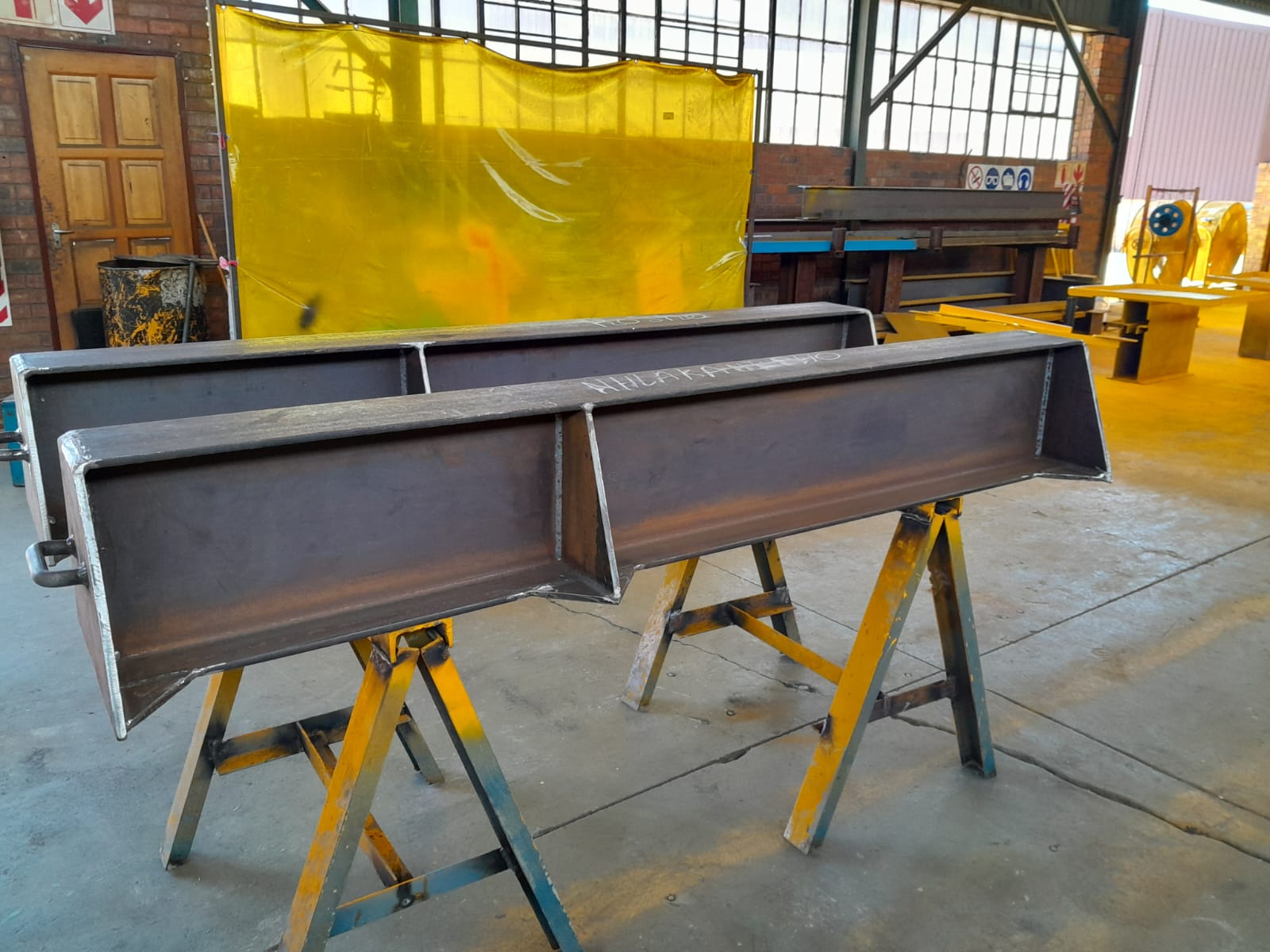 Steel beam assemblies on stands in a workshop.