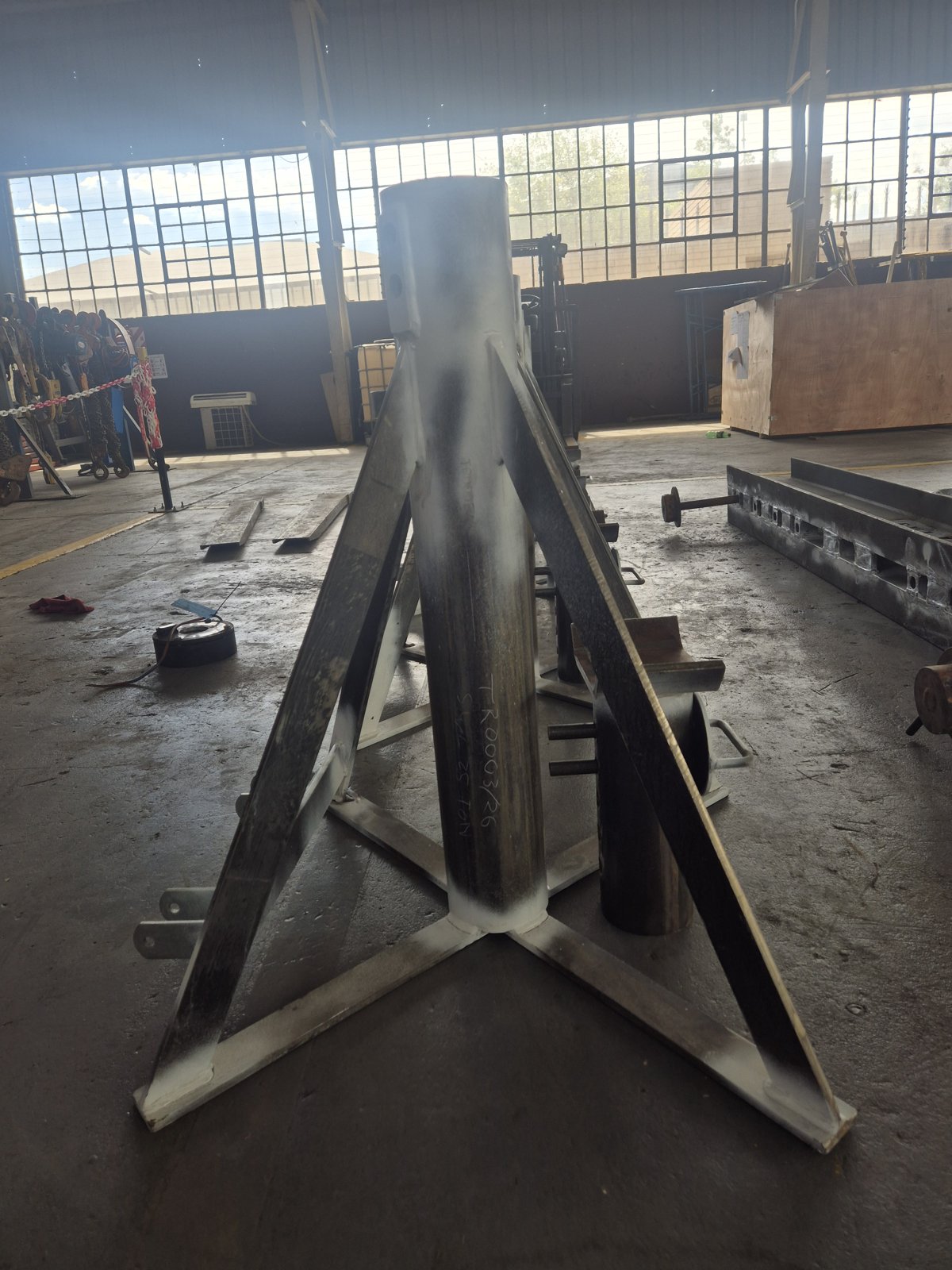 Steel assembly with a cylindrical section and triangular bracing in a workshop.