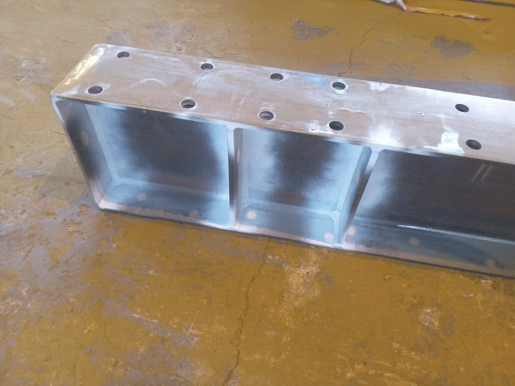 Steel component with welded internal stiffeners and drilled mounting holes.